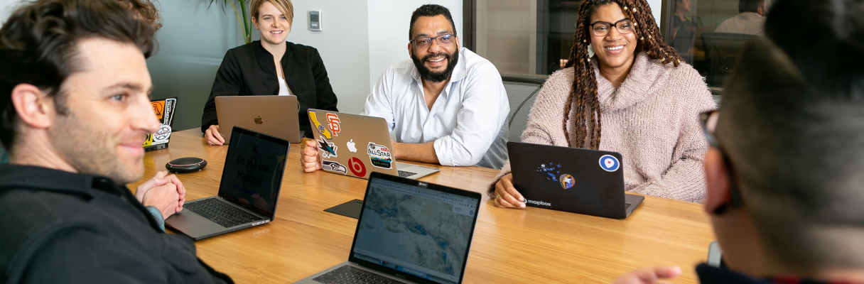 imagem colorida de pessoas com notebook em uma sala de reunião